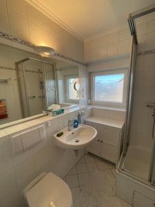 ein Bad mit einem Waschbecken, einem WC und einer Dusche in der Unterkunft Seestern in Hörnum