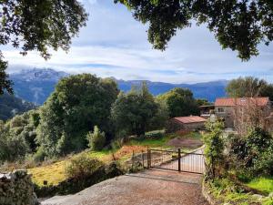 um portão numa colina com montanhas ao fundo em Chez Paulette - meublé de tourisme classé 3 étoiles em Zonza