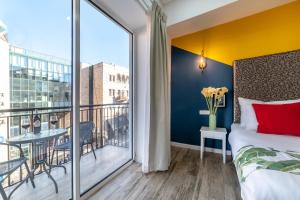 a bedroom with a bed and a balcony with a table at Paamonim Hotel Jerusalem in Jerusalem