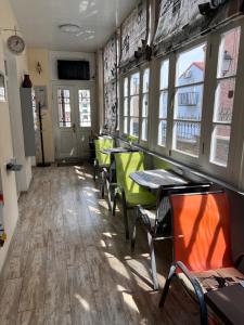 un restaurante con sillas verdes, mesas y ventanas en Tbil Home Hostel, en Tiflis