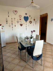 a dining room table with white chairs and hearts on the wall at Salento Casa Vacanza Il Focolare in Torchiarolo