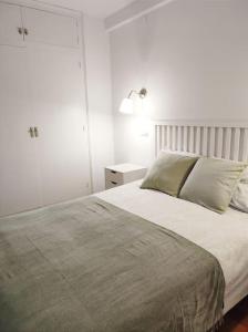 una camera bianca con un grande letto e una lampada di Apartament familiar tranquil a Platja d'Aro a Platja  d'Aro