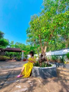 Una mujer con un vestido amarillo parada junto a un árbol en Ben Guesthouse Phu Quoc, en Phu Quoc