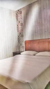 a bedroom with a large bed with a leather headboard at Pilatus Hotel Bandung in Bandung