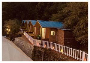 a row of houses with a fence next to a street at The Cocoon Camps & nature Resorts in Nainital