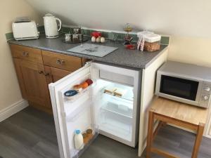 una piccola cucina con frigorifero aperto accanto a un forno a microonde di Oaks Barn a Chinnor