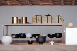 a shelf with cups and books on it at KUMU Kanazawa by THE SHARE HOTELS in Kanazawa