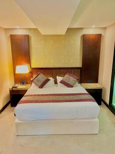 a bedroom with a large bed with two tables and a lamp at Royale Signature Hotel in Alor Setar