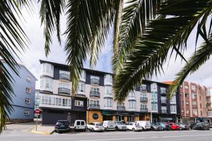 un gran edificio con coches estacionados en un estacionamiento en Hotel Oca Insua Costa da Morte, en Cee