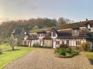 une ancienne maison avec une allée en gravier en face de celle-ci dans l'établissement Le Manoir by CauxCottes, à Vattetot-sur-Mer