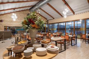 ein Restaurant mit Tischen und Stühlen und einer Vase aus Blumen in der Unterkunft Exe Astur Plaza in Astorga