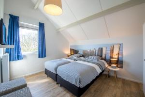 1 dormitorio con 2 camas y una ventana con cortinas azules en Hansa watersport & recreatie en Wilhelminadorp