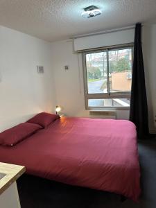 - une chambre avec un grand lit rouge et une fenêtre dans l'établissement Les Logis de Paray Appartement n1, à Paray-le-Monial