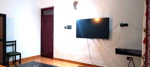 uma televisão de ecrã plano pendurada numa parede em Lairai's Happy Home em Candolim