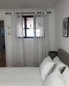 a bedroom with a bed with white curtains and a window at Accommodation in Sesimbra - Two Double Bedroom in Sesimbra
