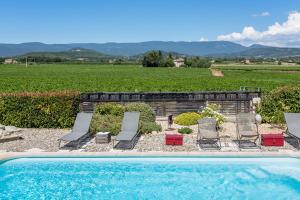 a pool with chairs and a view of a vineyard at Gîte Coquelicot in Gargas