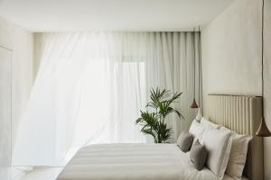 ein Schlafzimmer mit einem weißen Bett und einem Fenster in der Unterkunft Domes Miramare, a Luxury Collection Resort, Corfu - Adults Only in Moraḯtika