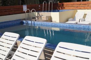 two white chairs and a swimming pool with some water at Studio Apartments Marija with private parking in Makarska