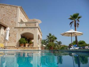 einen Pool mit Sonnenschirm neben einem Haus in der Unterkunft Chalets Torre Nova in Cala Santanyi