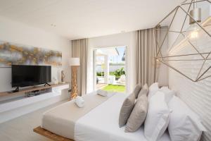 a white bedroom with a large bed and a tv at VILLA LILOU, Splendide villa au centre de Grand Baie in Grand Baie +226 photos