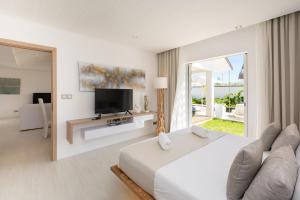 a white bedroom with a large bed and a television at VILLA LILOU, Splendide villa au centre de Grand Baie in Grand Baie