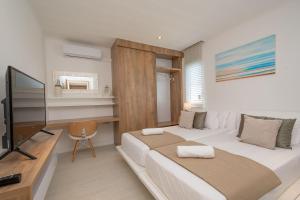 a bedroom with two beds and a desk and a television at VILLA LILOU, Splendide villa au centre de Grand Baie in Grand Baie