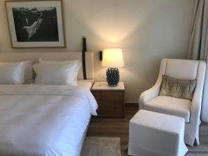 ein Schlafzimmer mit einem Bett, einem Stuhl und einer Lampe in der Unterkunft Domes Miramare, a Luxury Collection Resort, Corfu - Adults Only in Moraḯtika