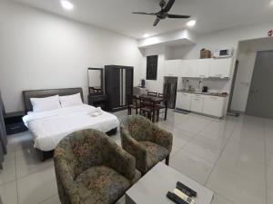 a bedroom with a bed and chairs and a kitchen at Peace home 23 in Cyberjaya
