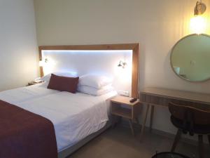 a bedroom with a white bed with a mirror and a chair at Residence Hotel in Netanya