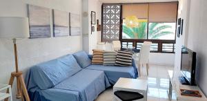 a living room with a blue couch and a table at Doñana Apartamento Sunset first line to the beach in Patalavaca