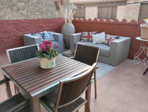 a patio with a wooden table and chairs and a couch at LES LLÚDRIGUES. Casa Loft con encantadora terraza in Arnés