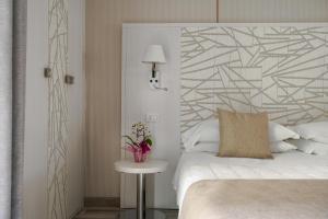 Grand Hotel Terme & SPA في تْشيانشانو تيرمي: غرفة نوم بسرير ابيض وطاولة بها ورد