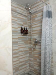 La salle de bains est pourvue d'une douche avec rideau de douche. dans l'établissement Olive - HappyHostGr - Downtown Apartment, à Vólos