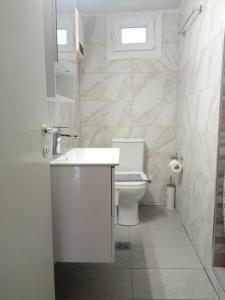 La salle de bains blanche est pourvue d'un lavabo et de toilettes. dans l'établissement Olive - HappyHostGr - Downtown Apartment, à Vólos
