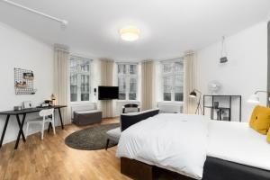 a white bedroom with a bed and a desk and a table at Ibsens Hotel in Copenhagen