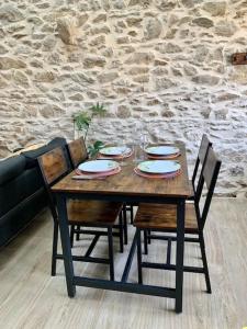 une table et des chaises en bois avec des assiettes et des verres dans l'établissement Le cocon sauternais avec balneo, à Preignac