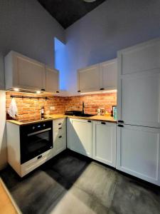 cocina con electrodomésticos blancos y pared de ladrillo en Tatarska Sen Apartamenty, en Przemyśl