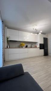 a kitchen with white cabinets and a black refrigerator at Apartment Luxury in Râmnicu Vâlcea