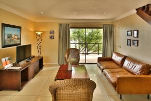 Una sala de estar con un sofá de cuero y un televisor. en Galico Holiday Home, en Langebaan