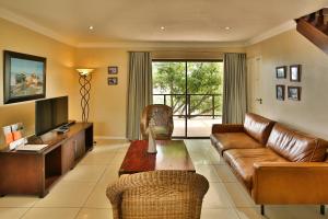 a living room with a leather couch and a television at Galico Holiday Home in Langebaan