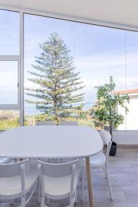 una mesa blanca y sillas frente a una gran ventana en Coastal Vista: retreat in nature, en Bajamar