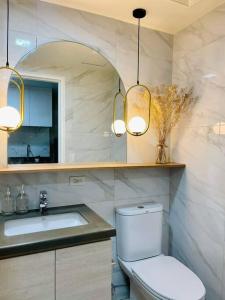 a bathroom with a toilet and a sink and lights at Stunning Bayview Studio in Cebu in Guizo