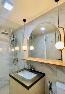 La salle de bains est pourvue d'un lavabo, d'une douche et de lumières. dans l'établissement Stunning Bayview Studio in Cebu, à Guizo