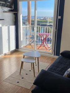 a living room with a table and a chair and a balcony at Studio vue sur mer in La Chaume