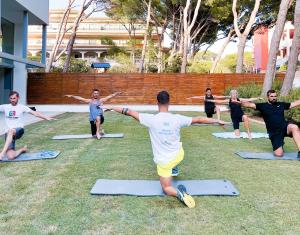 eine Gruppe von Leuten, die Yoga im Gras machen in der Unterkunft Diamant Hotel & Aparthotel in Cala Ratjada