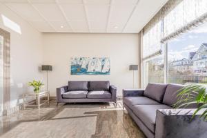 a living room with two couches and a large window at Hotel Bellevue in Timmendorfer Strand