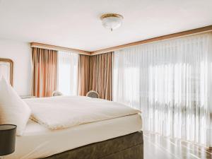 ロイカーバートにあるThermalhotel Regina Termeのベッドルーム(白いベッド1台、窓付)