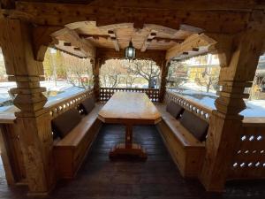 a wooden pavilion with a wooden table and benches at Casa Botiza - Cătun in Sinaia