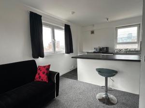 a living room with a black couch and a kitchen at Spacious,1 bed, balcony, Southwark Central London in London