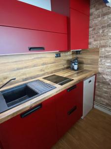 - une cuisine avec des placards rouges et un évier dans l'établissement Studio vue sur mer, à La Chaume